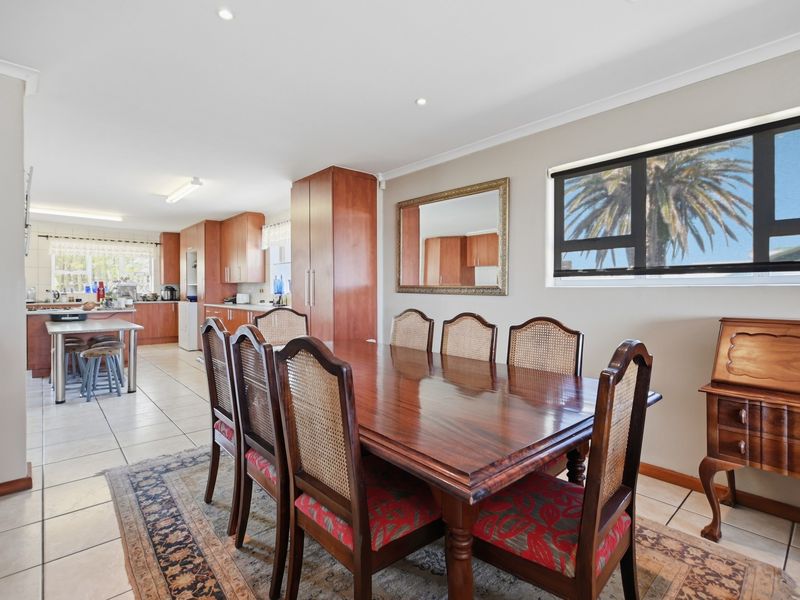 Spacious open-plan dining and kitchen area featuring tiled flooring, ample built-in cabinetry, and natural light through large windows.