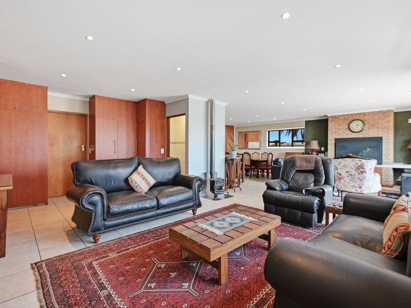Spacious open-plan living area featuring tiled floors, recessed lighting, built-in cabinetry, and a prominent brick fireplace with a freestanding wood-burning stove.