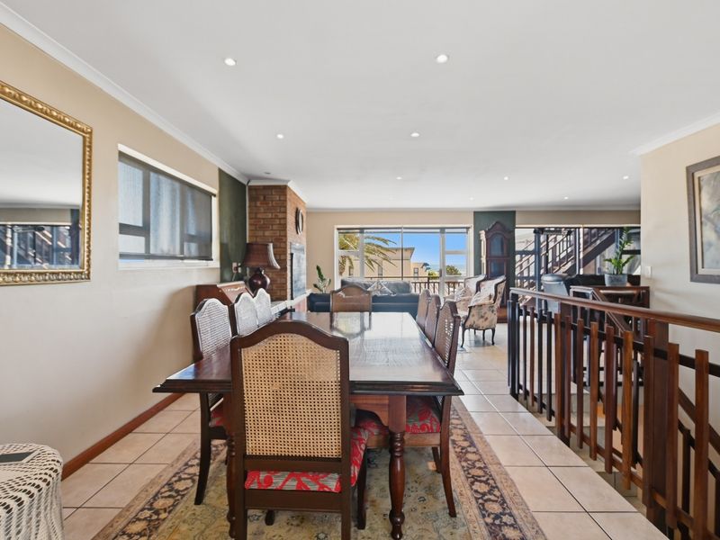 Spacious dining area featuring tiled flooring, recessed lighting, and a brick fireplace, with an open-plan layout leading to a staircase and outdoor access.