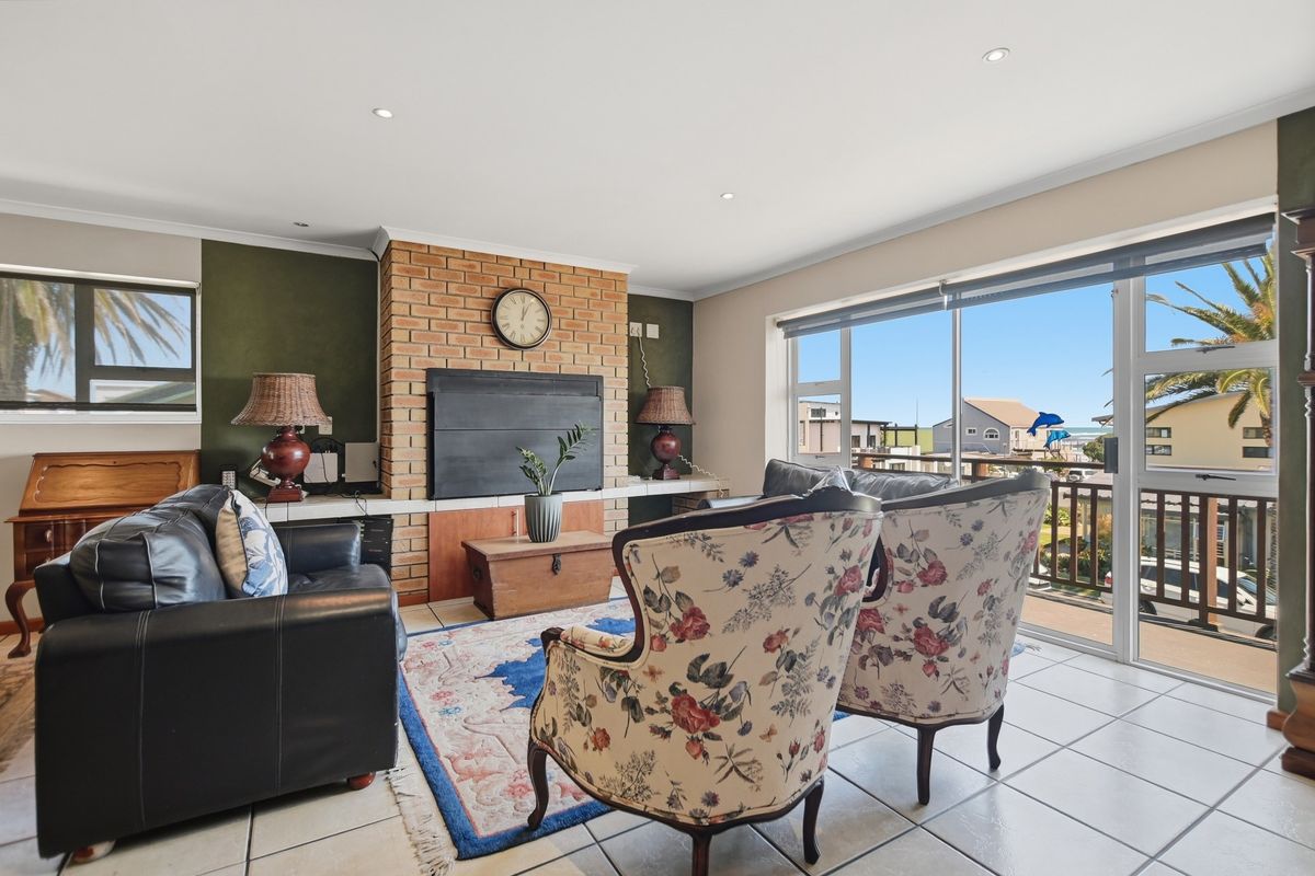 A bright living room featuring a prominent brick fireplace, tiled flooring, and large sliding glass doors that open onto a balcony with exterior views.