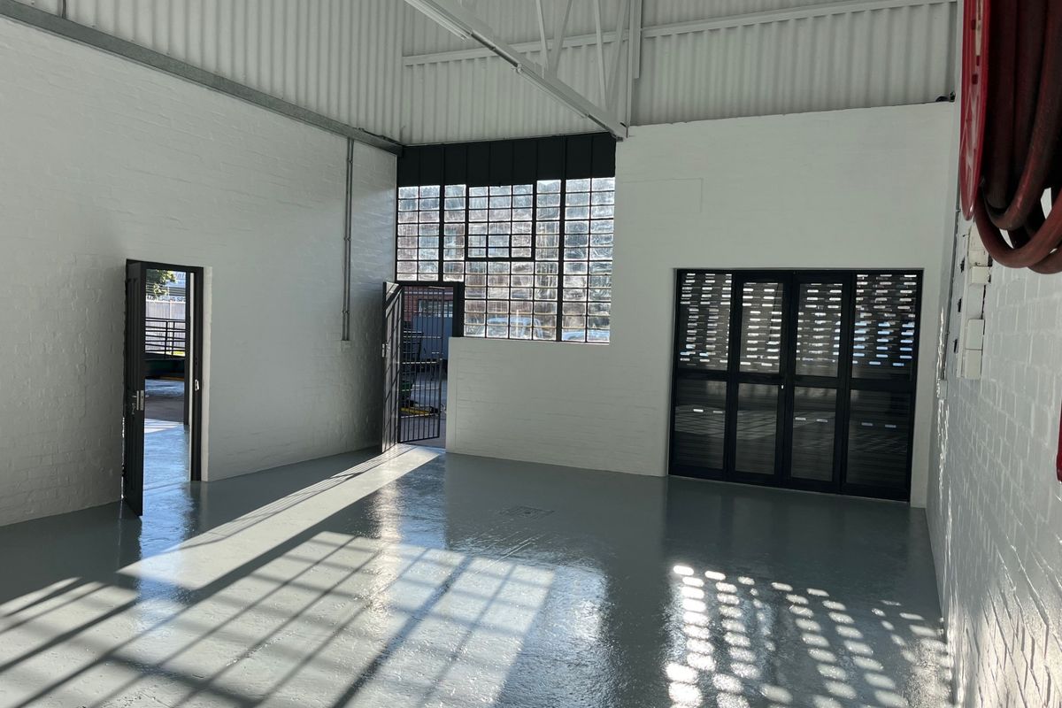 Spacious industrial utility area featuring high ceilings with exposed steel trusses, polished epoxy flooring, and large steel-framed windows providing ample natural light.