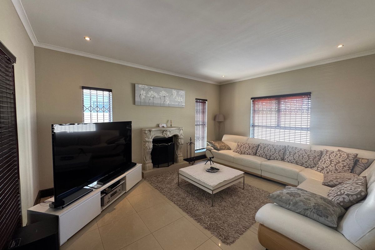 Spacious living room featuring tiled flooring, recessed downlights, and a decorative fireplace, creating a comfortable and well-lit area for relaxation.