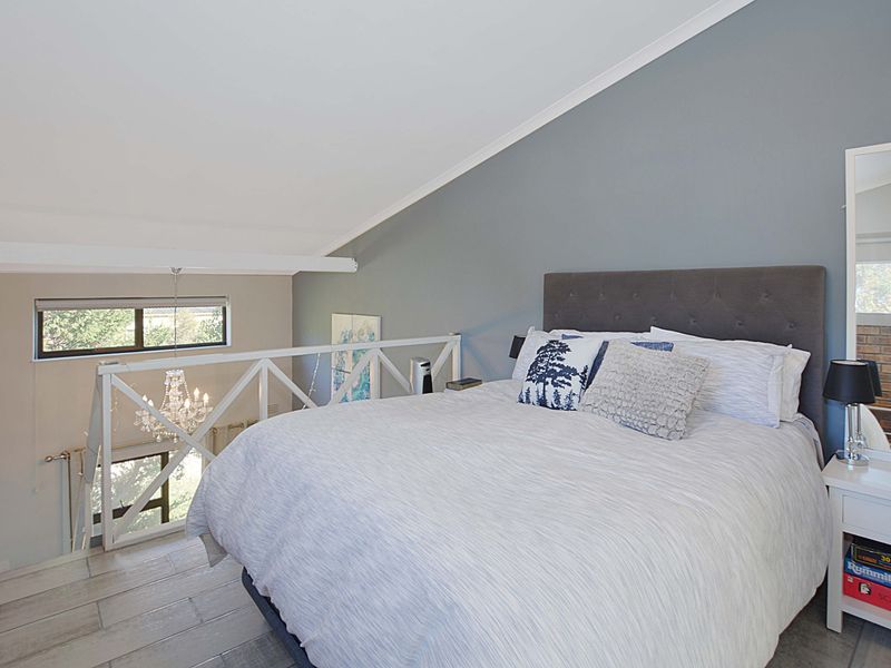 A spacious loft-style bedroom featuring a vaulted ceiling, tiled flooring, and a protective railing overlooking the lower level.