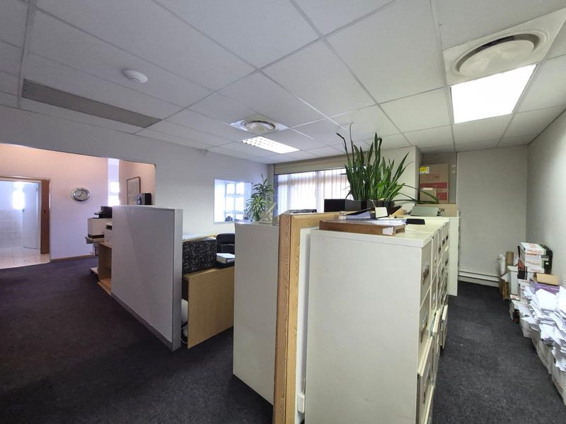 A functional commercial office space featuring partitioned work areas, suspended ceilings with recessed lighting, and carpeted flooring.