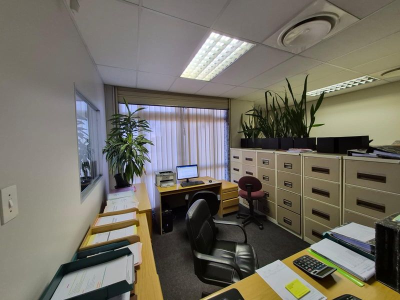 A functional commercial office space featuring a suspended ceiling, recessed lighting, vertical blinds, and extensive built-in filing cabinet storage.