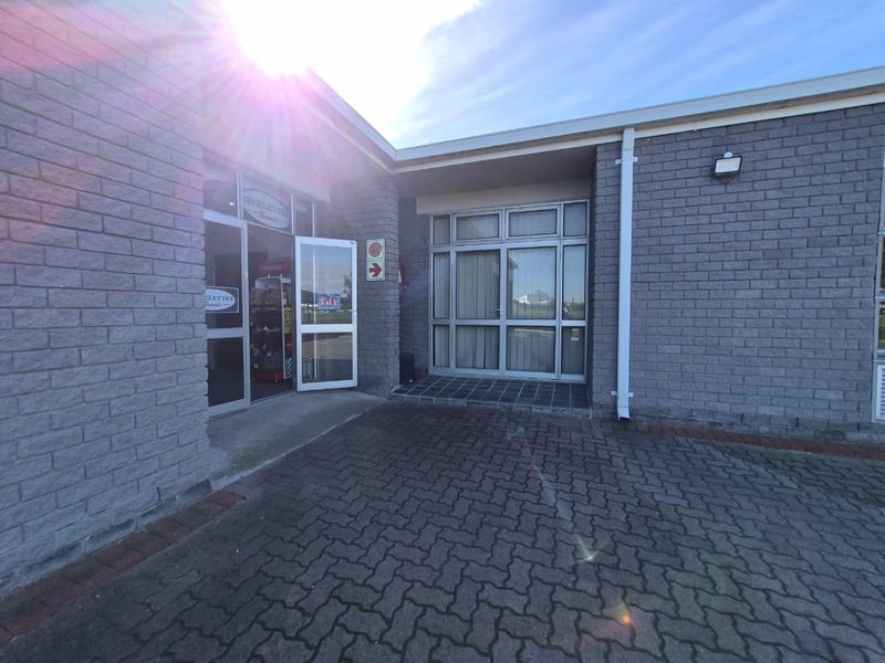 Front entrance of a commercial property featuring a brick facade, paved driveway, and aluminium framed glass doors and windows.