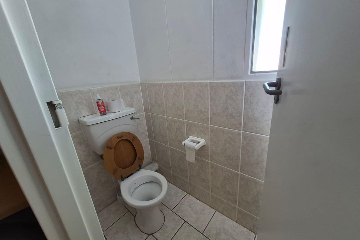 A functional, compact guest bathroom featuring ceramic wall and floor tiling, a standard toilet, and a frosted window for natural light.