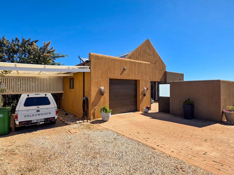 Front exterior view of the property featuring a paved driveway, a single garage, and a covered carport area.