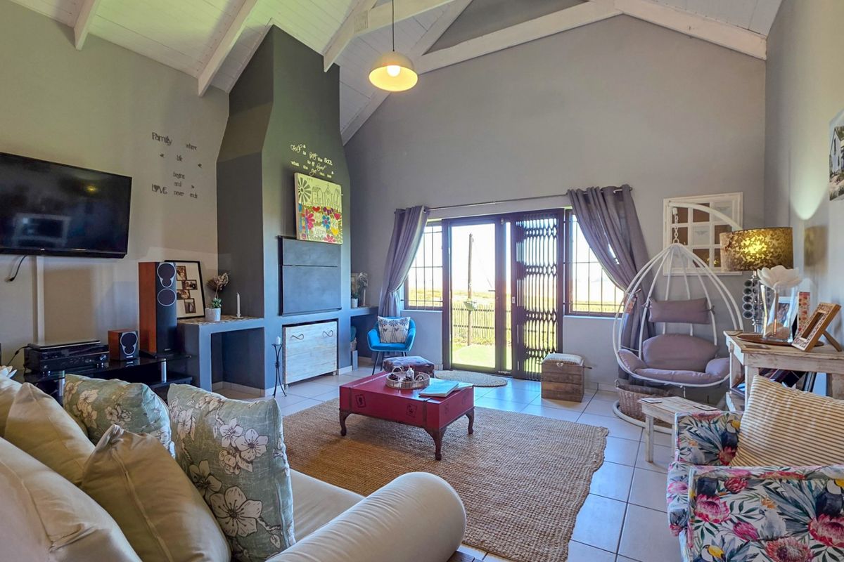 Spacious living room featuring a high vaulted ceiling with exposed rafters, a prominent built-in fireplace, and direct access to the outdoors via sliding doors.