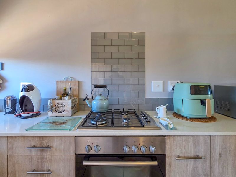A modern kitchen workspace featuring a gas hob, built-in oven, stone countertops, and a stylish subway tile splashback.