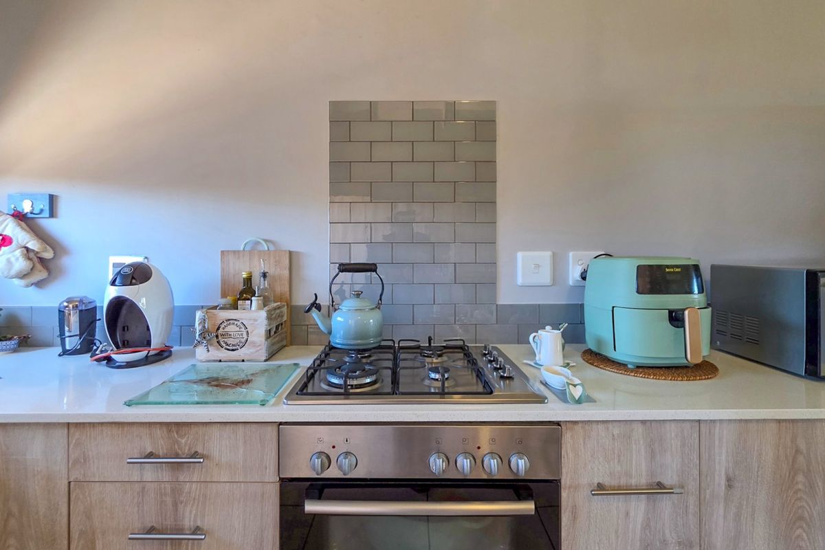 A modern kitchen workspace featuring a gas hob, built-in oven, stone countertops, and a stylish subway tile splashback.