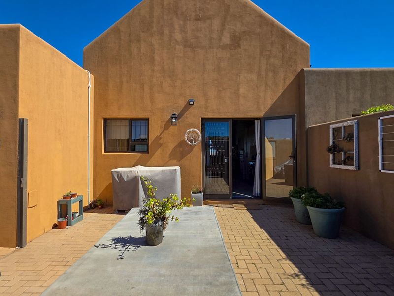 A private rear courtyard featuring paved flooring, stucco walls, and direct access to the interior through double glass doors.