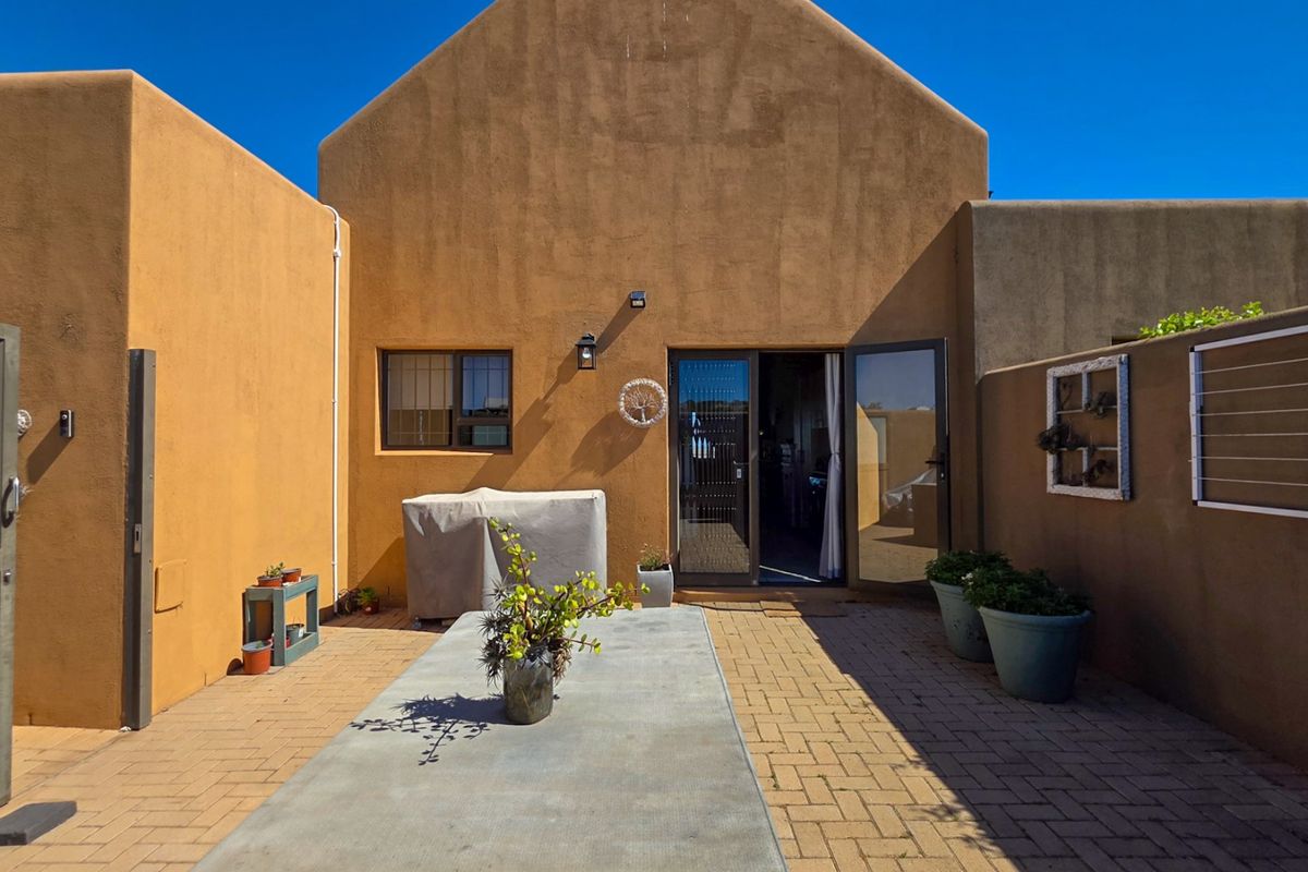 A private rear courtyard featuring paved flooring, stucco walls, and direct access to the interior through double glass doors.