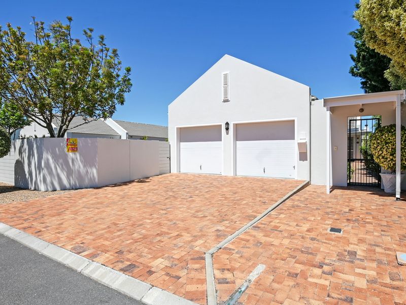 Front view of the property featuring a double garage, paved driveway, and a secure gated entrance.