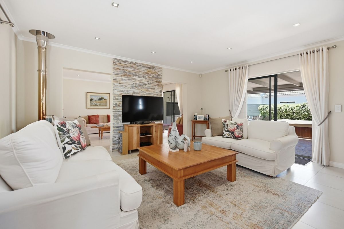 Spacious living room featuring a stone accent wall, a modern freestanding fireplace, and large sliding glass doors providing access to the outdoor patio area.