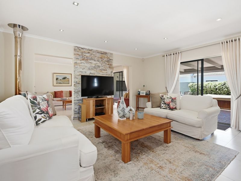 Spacious living room featuring a stone accent wall, a modern freestanding fireplace, and large sliding glass doors providing access to the outdoor patio area.