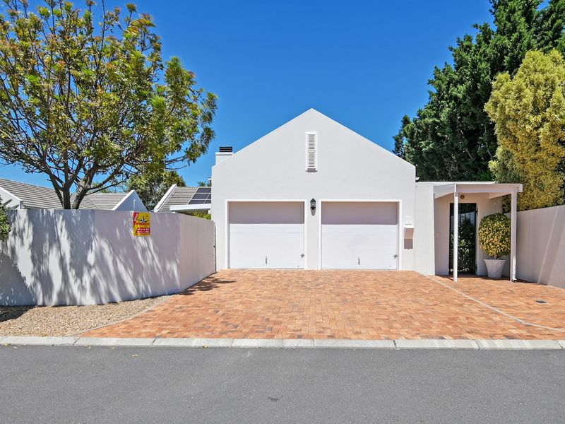 Front elevation of a residential property featuring a double garage, paved driveway, and a covered entrance area with clean white exterior finishes.