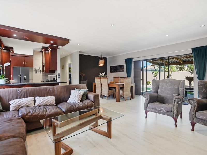 Spacious open-plan living and dining area featuring modern laminate flooring, recessed lighting, and seamless flow to the outdoor patio through large sliding glass doors.