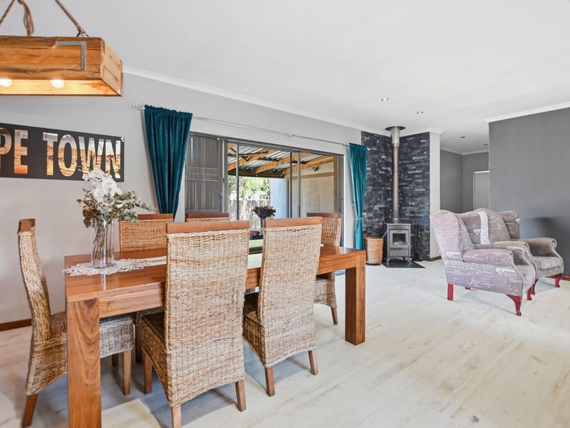 Spacious living area featuring a stone-clad wood-burning fireplace, modern laminate flooring, and large sliding glass doors providing access to the outdoor patio.