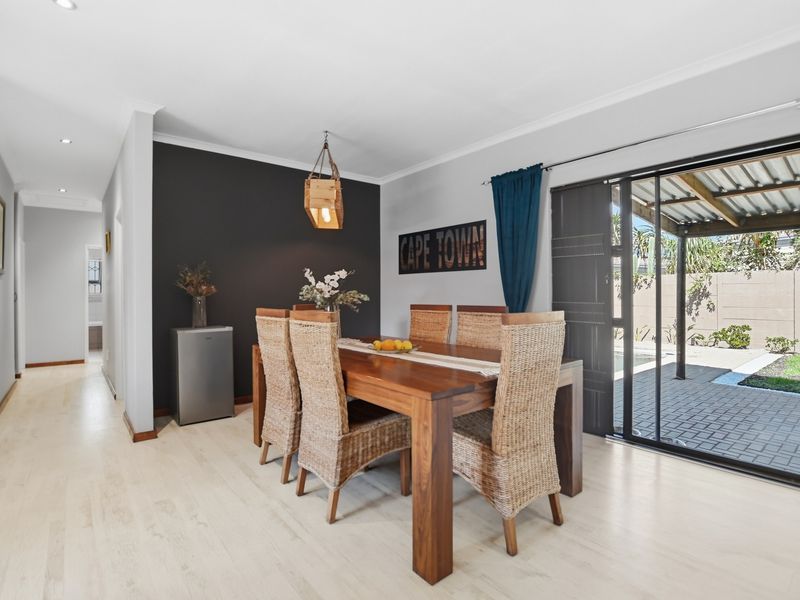 Bright dining area featuring modern laminate flooring, a striking dark accent wall, and large sliding glass doors providing seamless access to the outdoor patio.