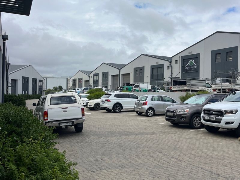 Exterior view of a commercial business park featuring multiple warehouse units with paved parking and access roads.