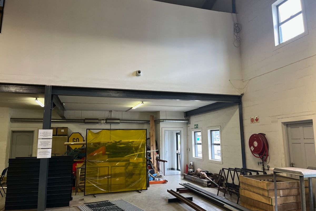 Spacious commercial utility or workshop area featuring high ceilings, exposed steel structural beams, concrete flooring, and integrated fire safety equipment.