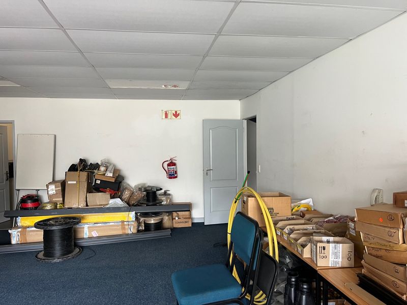 A functional utility or storage space featuring a suspended ceiling, internal door access, and a wall-mounted fire extinguisher.