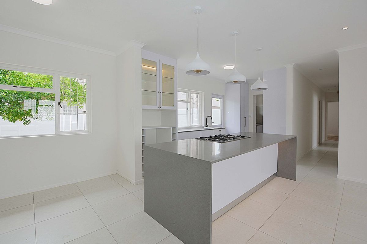 Modern kitchen featuring a central island with a built-in gas cooktop, sleek cabinetry, and tiled flooring in a bright, open-plan layout.