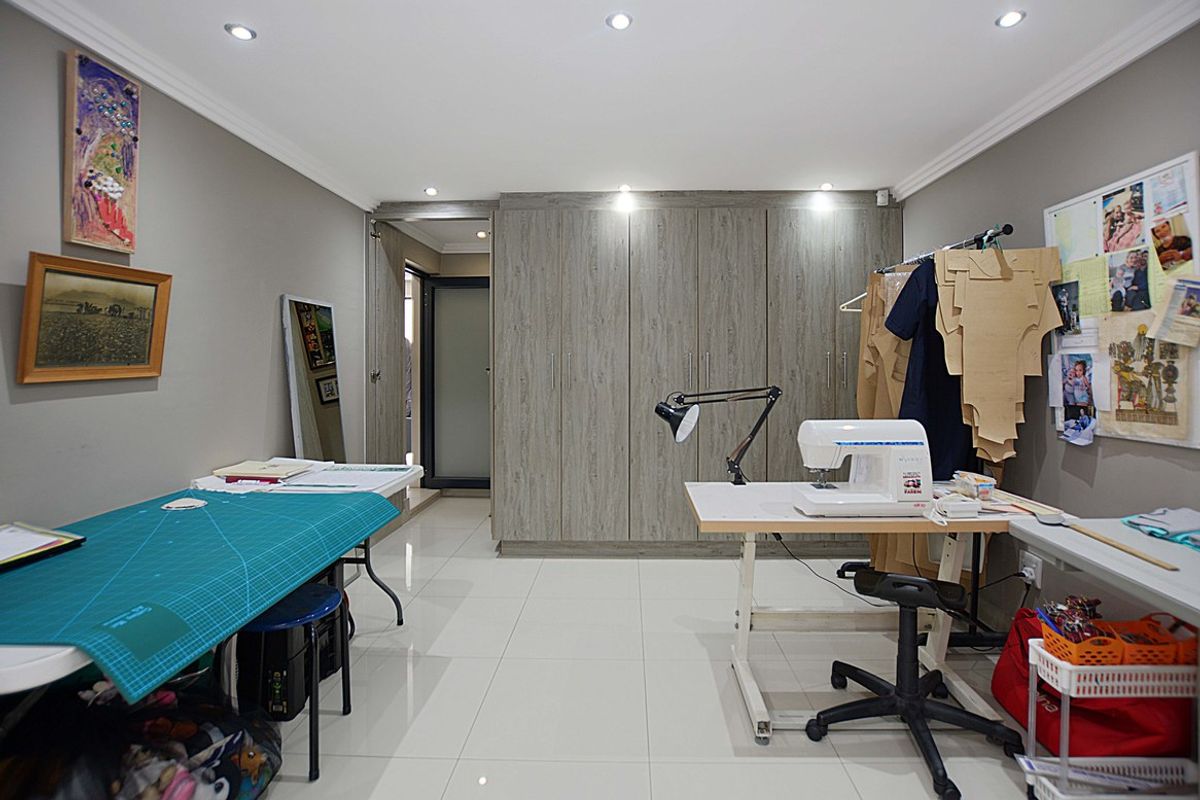 A versatile room featuring built-in floor-to-ceiling cabinetry, recessed downlighting, and polished tile flooring, currently utilized as a functional workspace.