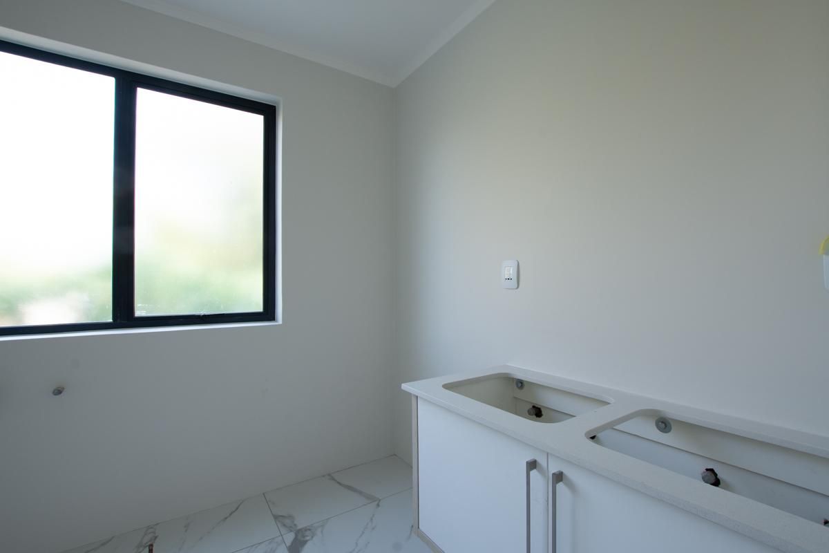 A bright, modern bathroom featuring a double vanity unit with stone countertop, marble-look floor tiles, and a large window providing natural light.