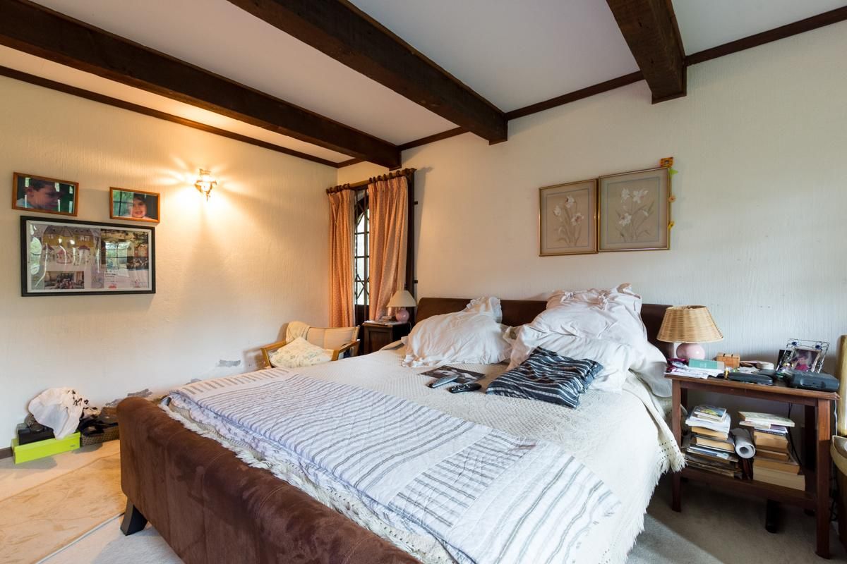 A bedroom featuring exposed timber ceiling beams and a classic layout with access to an adjacent outdoor area.