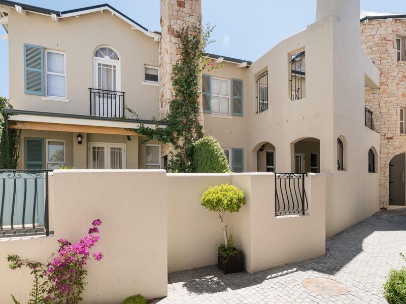 A well-maintained exterior view of the apartment complex featuring stone masonry, wrought iron accents, and a paved driveway entrance.