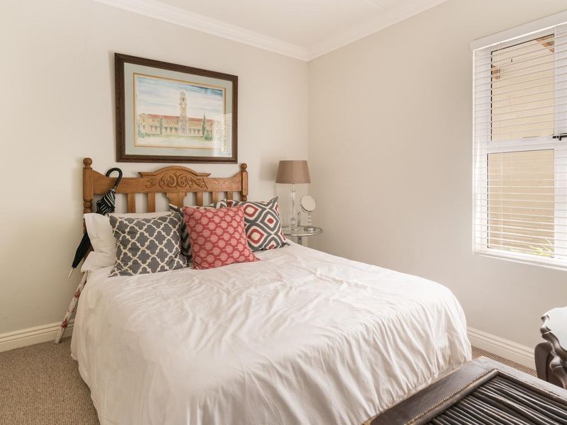 A well-lit bedroom featuring neutral walls, carpeted flooring, and a built-in wardrobe, offering a comfortable and functional living space.