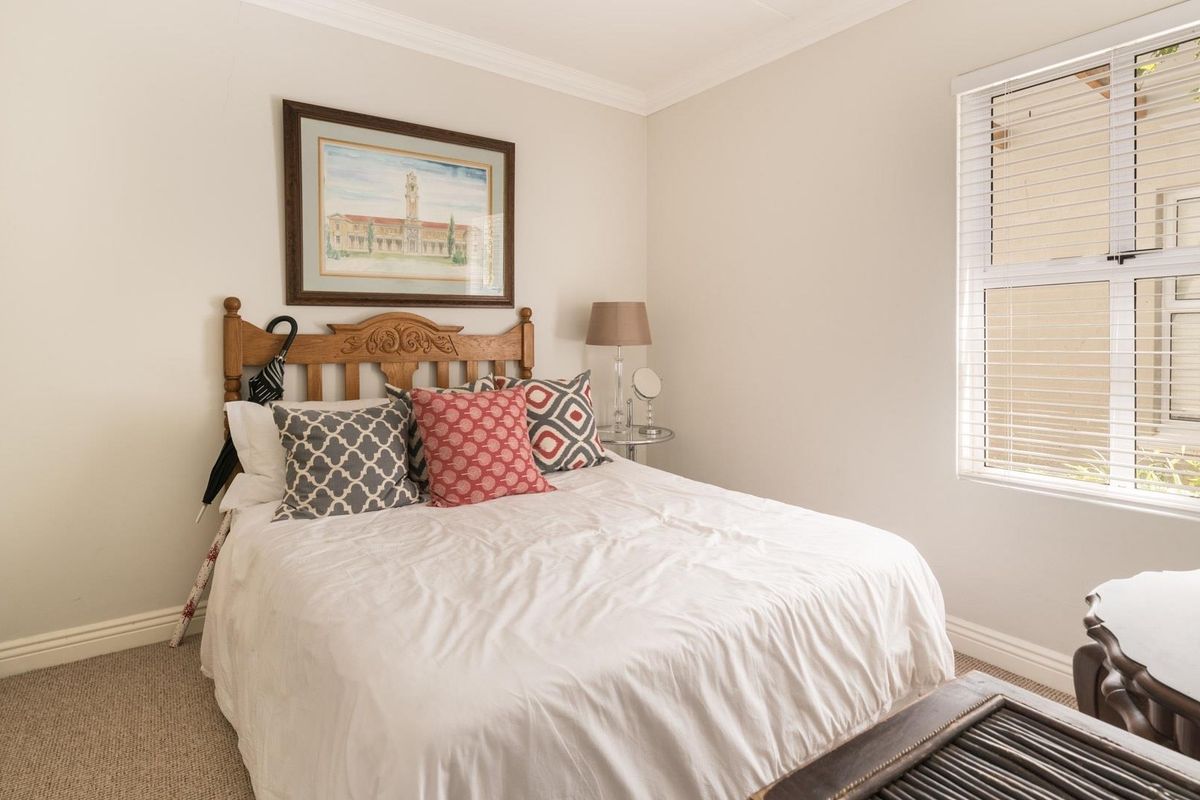 A well-lit bedroom featuring neutral walls, carpeted flooring, and a built-in wardrobe, offering a comfortable and functional living space.
