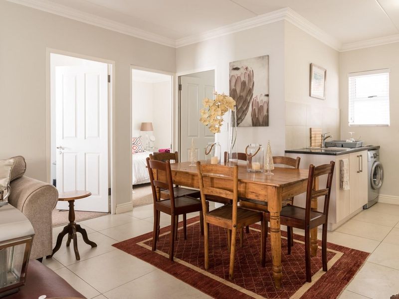 Open-plan living and dining area featuring tiled floors, coving, and a compact kitchen corner with integrated laundry facilities.