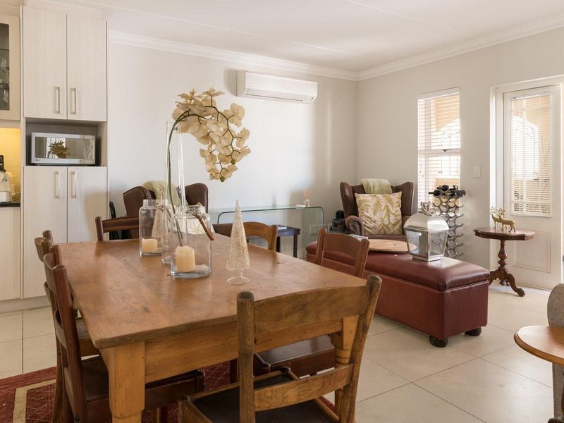 Open-plan living and dining area featuring a modern kitchen with built-in appliances, tiled flooring, and direct access to an outdoor patio space.