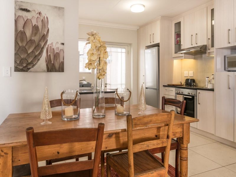 Open-plan kitchen and dining area featuring light wood cabinetry, integrated appliances, and tiled flooring, creating a functional and cohesive living space.