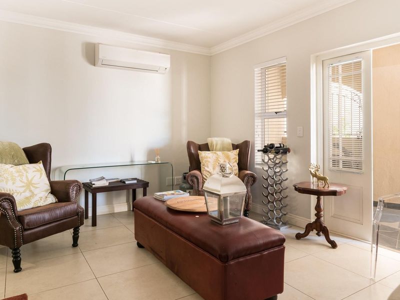 A bright and well-maintained living room featuring tiled flooring, a wall-mounted air conditioning unit, and direct access to an outdoor area.