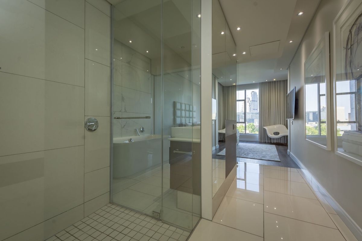 Modern bathroom featuring a glass-enclosed shower, sleek floor tiles, and recessed lighting, seamlessly integrated into the open-plan living space.