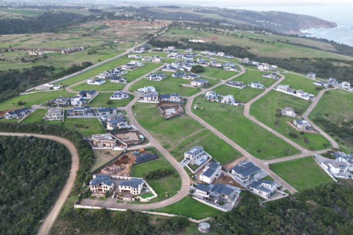 Aerial view of a residential estate development featuring multiple established homes, paved road infrastructure, and expansive green spaces overlooking the coastline.
