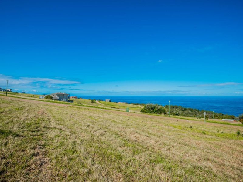 A wide-angle view of a vacant residential plot featuring expansive coastal and ocean vistas with established road infrastructure.