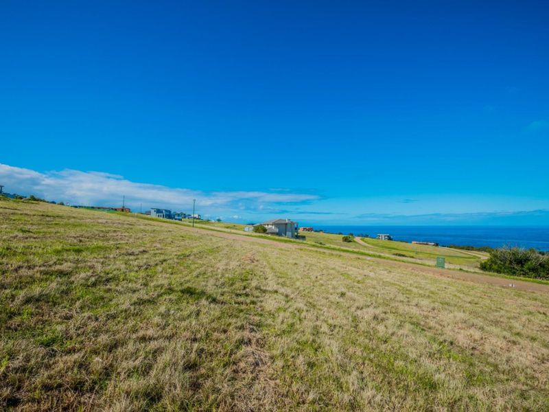 A wide-angle view of a sloped residential vacant land plot featuring expansive coastal and ocean vistas.