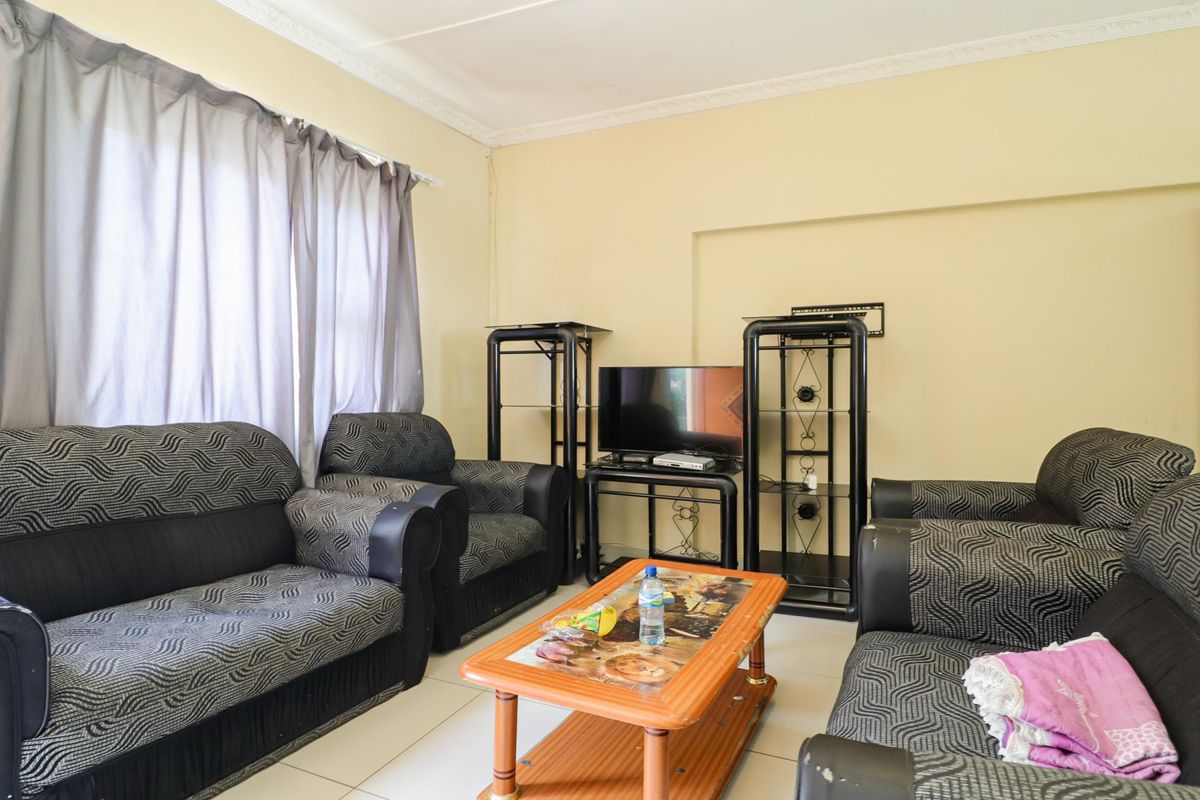 A functional living room featuring tiled flooring, crown molding, and large windows with curtain tracks.