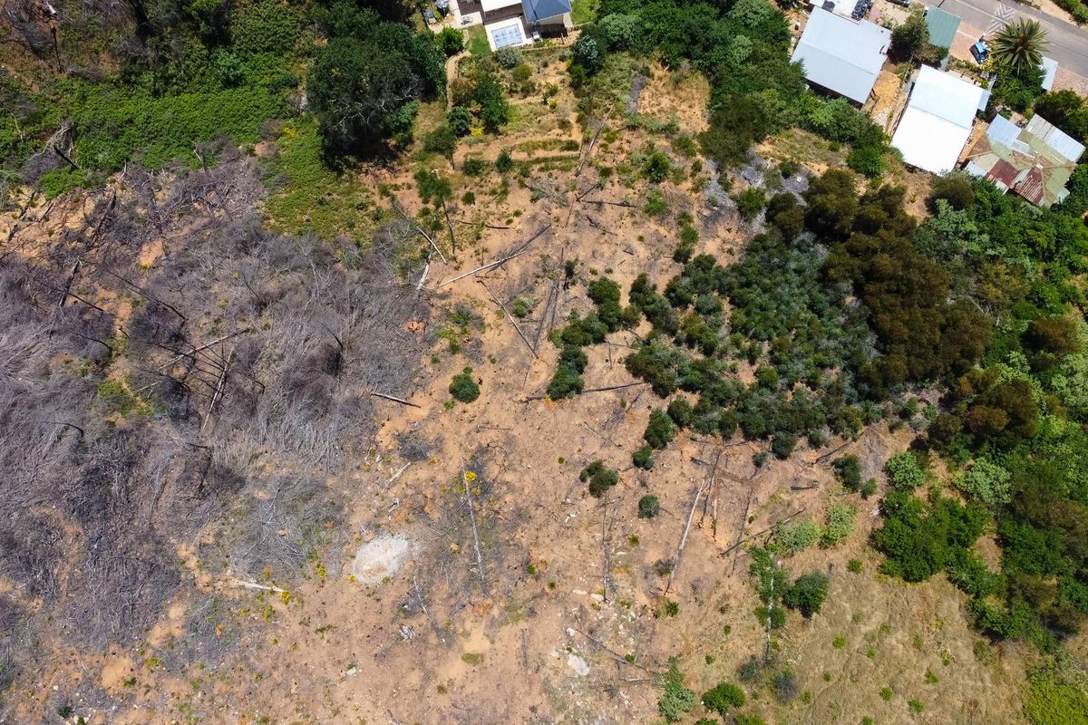 Aerial view of a vacant residential land parcel featuring a mix of cleared ground and natural vegetation, situated near existing residential properties.