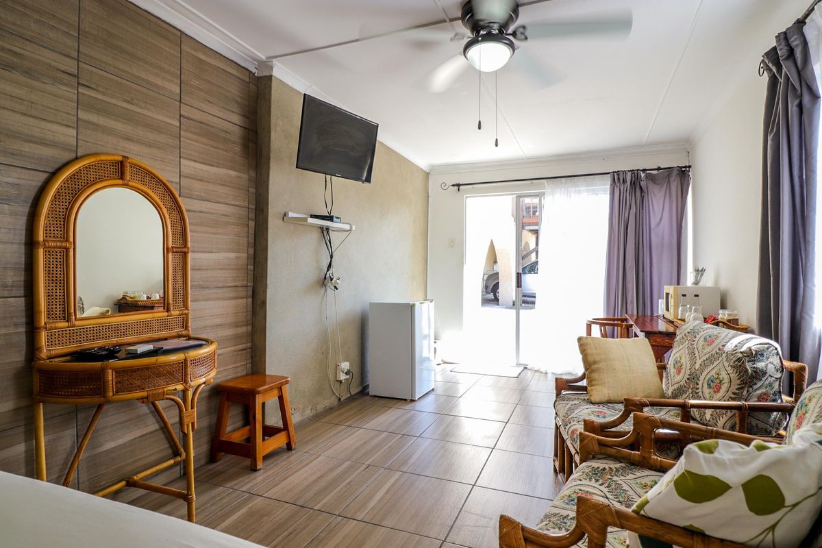 A living area featuring tiled flooring, a ceiling fan, and sliding glass doors providing access to the exterior.