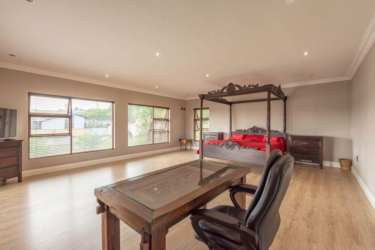 Spacious bedroom featuring light wood-look flooring, recessed ceiling lighting, and large windows with fitted blinds.