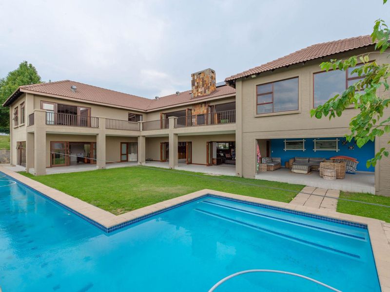 Spacious rear exterior view featuring a large swimming pool, manicured lawn, and a covered patio area with direct access to the main residence.