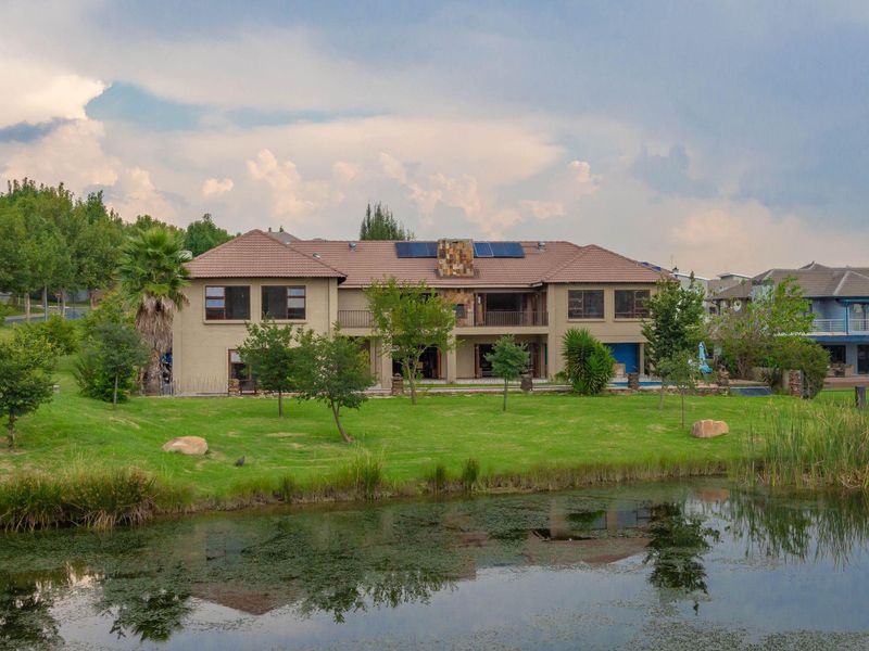 A spacious two-story residential property featuring a tiled roof, solar panels, and a rear garden overlooking a tranquil pond.