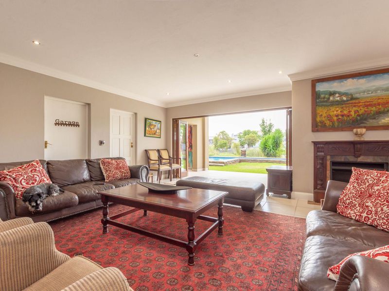 Spacious living room featuring a traditional fireplace, recessed lighting, and large folding doors that open onto a patio with garden and pool views.