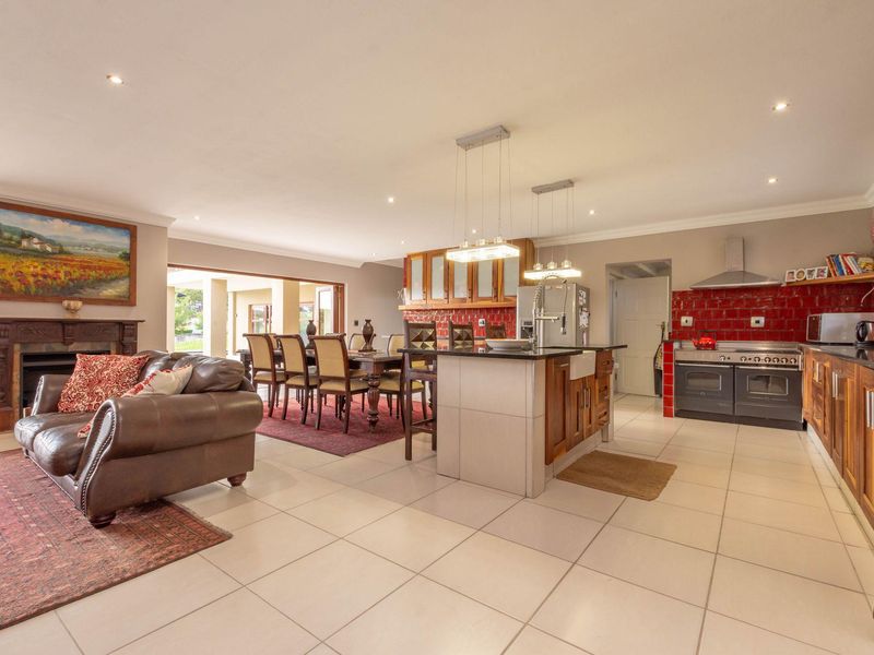 Spacious open-plan living and kitchen area featuring a central island, built-in oven with extractor fan, tiled flooring, and a traditional fireplace.